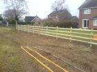 Post &amp; rail fencing with rabbit wire adjacent to farmland.
